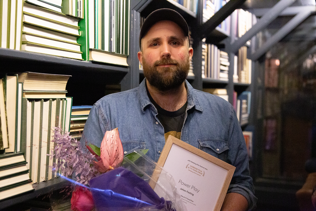 A man posing with flowers and award